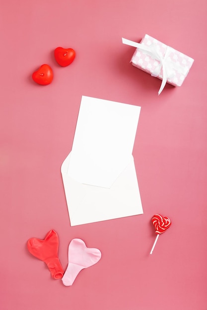 White envelopes with mock up paper for text around box with gift balloons and heart shaped candles