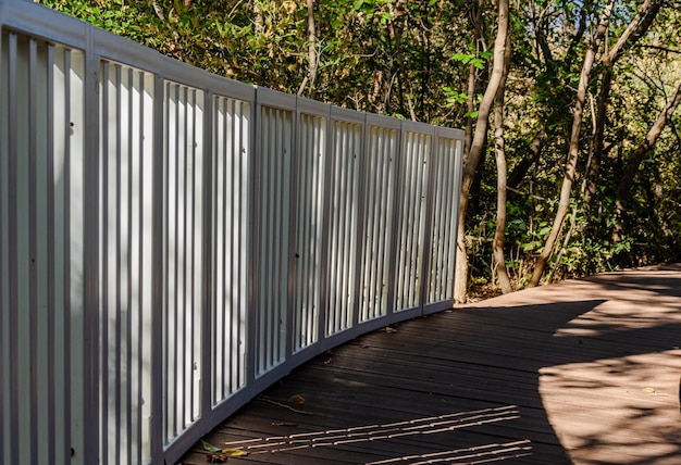 Photo a white fence on a boardwalk in the woods.