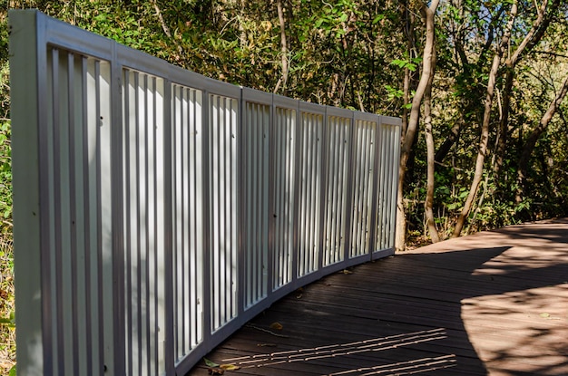 Photo a white fence on a walkway with trees in the background