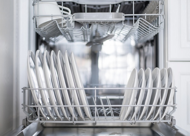 White flat plates large and small are loaded into the dishwasher