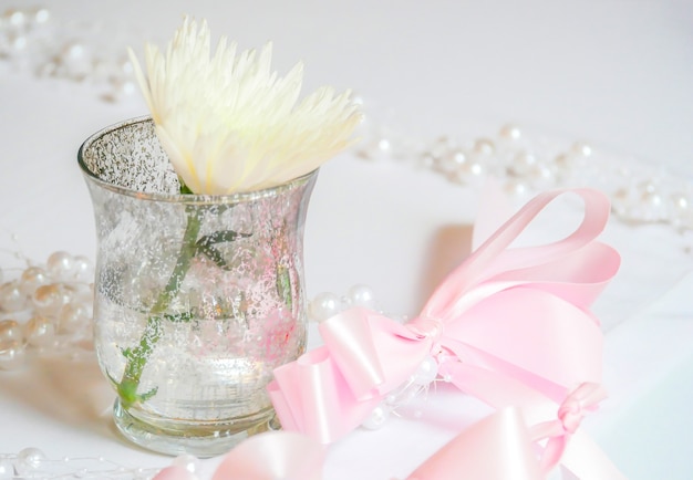 white flower in a little vase and pink bow ribbon