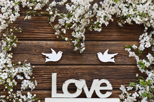 white Flowering Cherry Tree branches with two wooden birds and letters love.