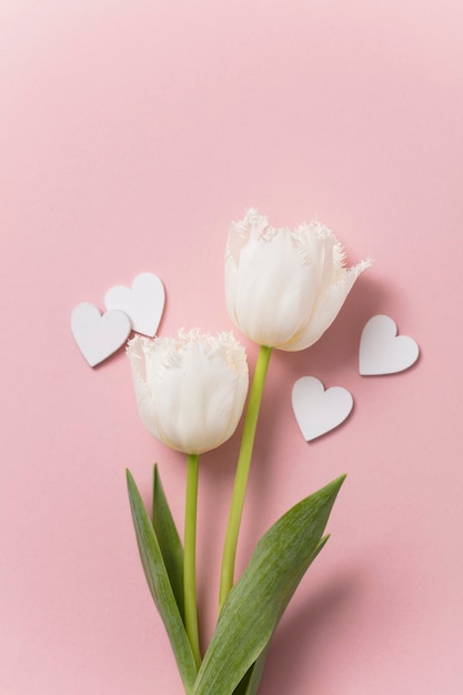 White flowers and hearts on a pastel pink background