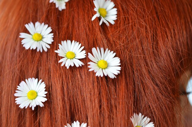 White flowers in red hair closeup