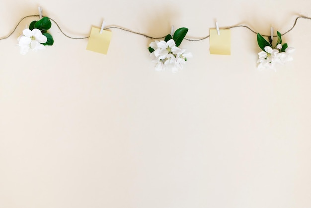 White flowers suspended on a string with wooden clothespins and pieces of paper for notes