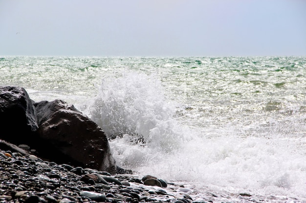 White foam waves breaking on black stones