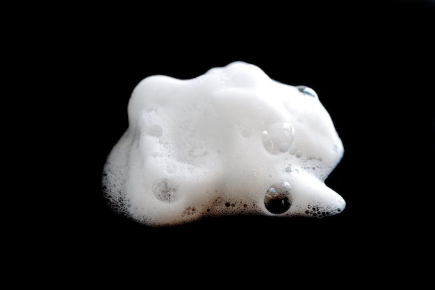 White foam with bubbles from soap, cleanser or shampoo isolated on black background close-up