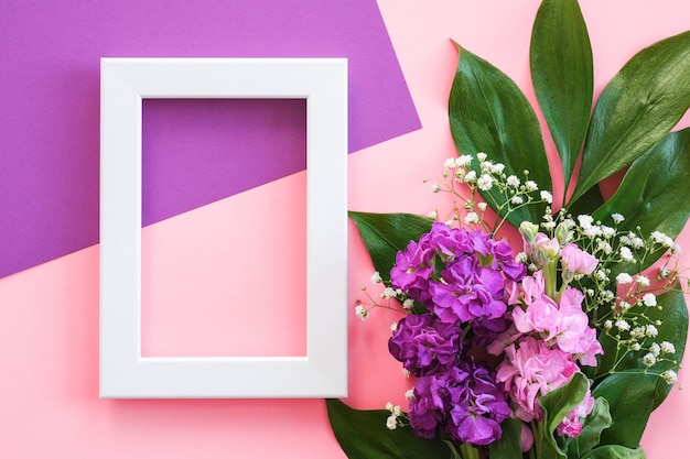 White frame and bouquet flowers on pink purple