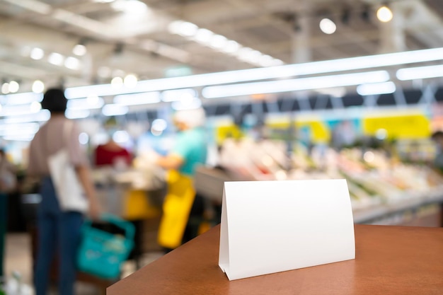 White framed sign on the table in the supermarket mockup mini sign layout for menu sign label text