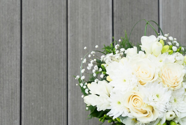 White fresh roses freesia and mum flowers wedding bouquet on wooden background