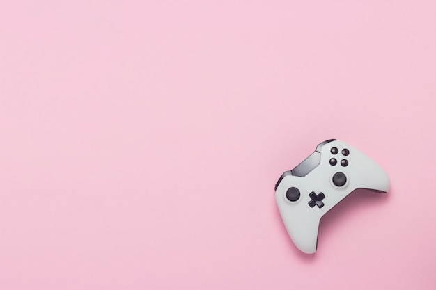 White gamepad on a pink background. Concept game on the console, computer games. Flat lay, top view.