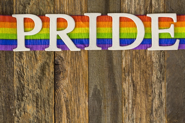 White Gay Pride sign on wood background.