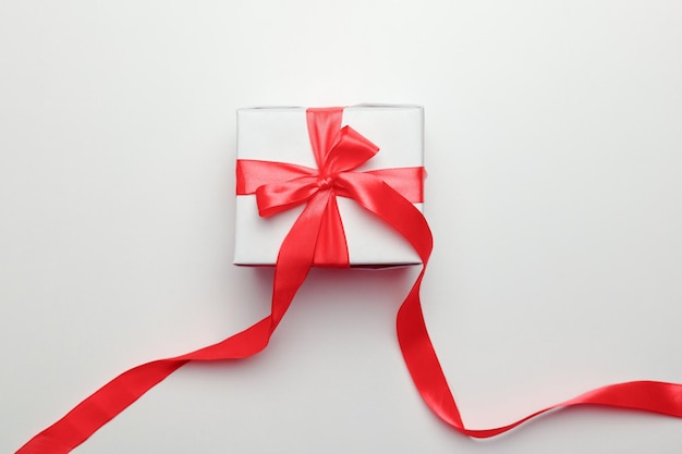 White gift box with red ribbon, isolated on white background