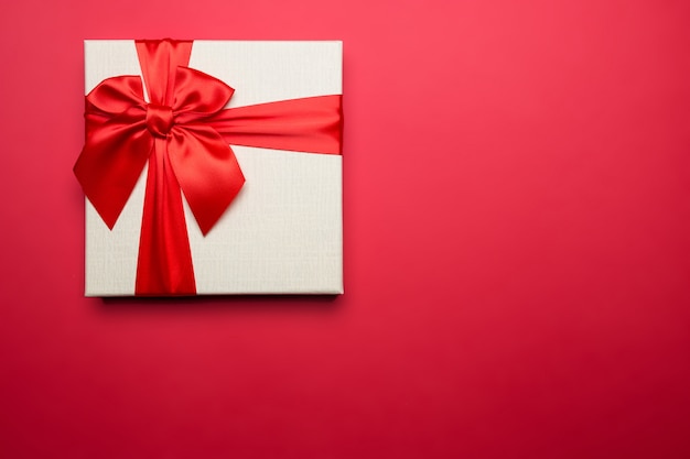 White gift box with red ribbon on red 