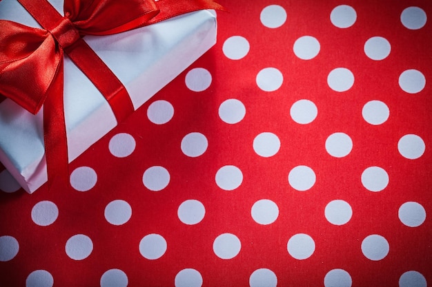 White gift box with tied ribbon on polkadot red fabric celebrations concept