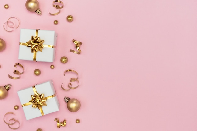 White gift boxes, golden decorations and ornaments on pastel pink background. Flat lay, copy space.