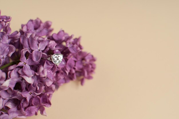 A white gold ring with a precious transparent stone in lilac purple colors on a beige background with a place for text