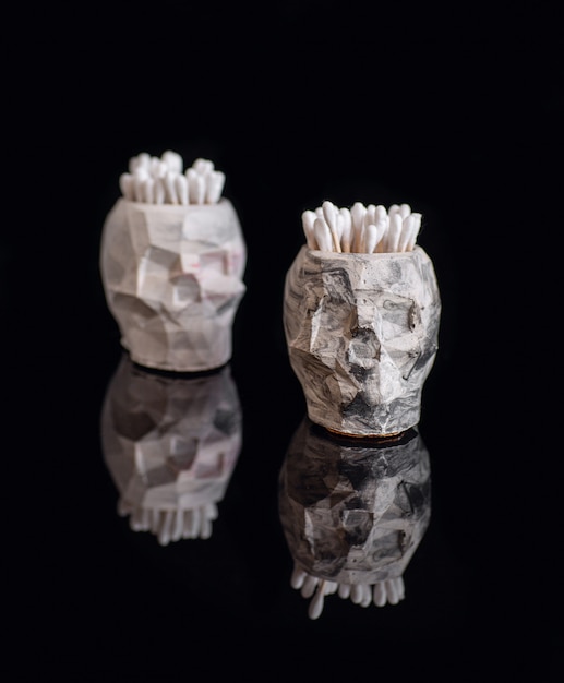 White and grey pots in the shape of skull  isolated on black acrylic