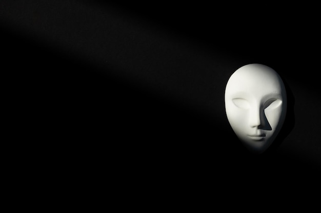 White gypsum mask of human with closed eyes on black background