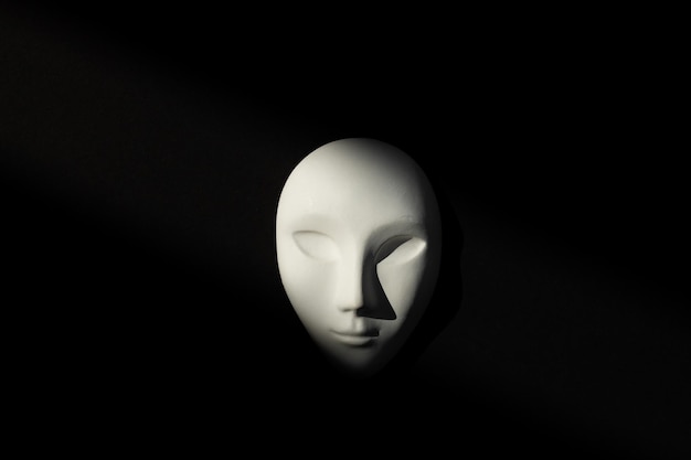 White gypsum mask of human with closed eyes on black background