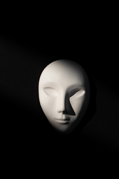 White gypsum mask of human with closed eyes on black background