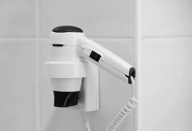 White hair dryer on holder in bathroom