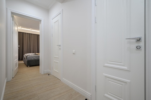 White hallway connected to bedroom with doors