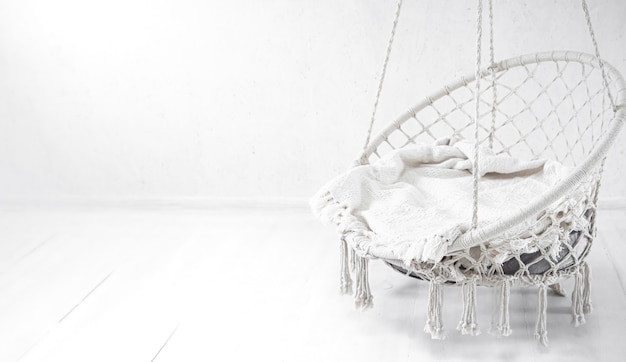 White hammock chair on white wall. Cozy place for weekend relax in the room copy space.