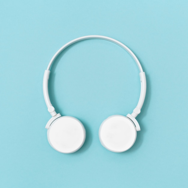 White headphones on blue sky colored paper background. Music concept. Dj Headset. Minimal style.