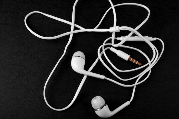 White headphones lying on a black background