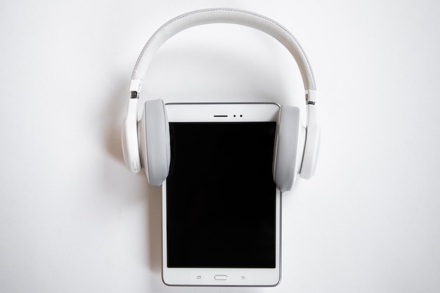 white headphones put on a white tablet on a white background