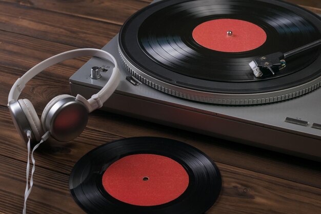 White headphones and a vinyl record player on a wooden background