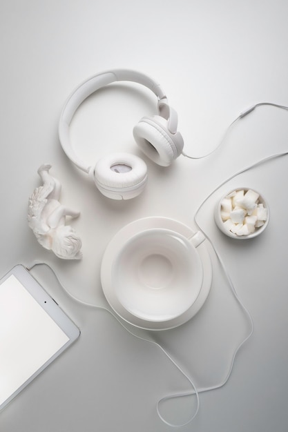 White headphones and a white cup on a white table