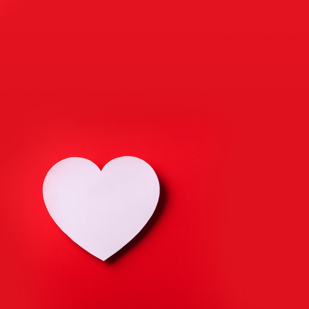 White heart cutted from paper over red background with copy space. Valentine's Day. Love, date, romantic concept. 