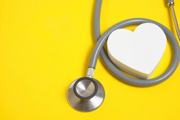 White heart and stethoscope on yellow backgroundHeart disease medical examination