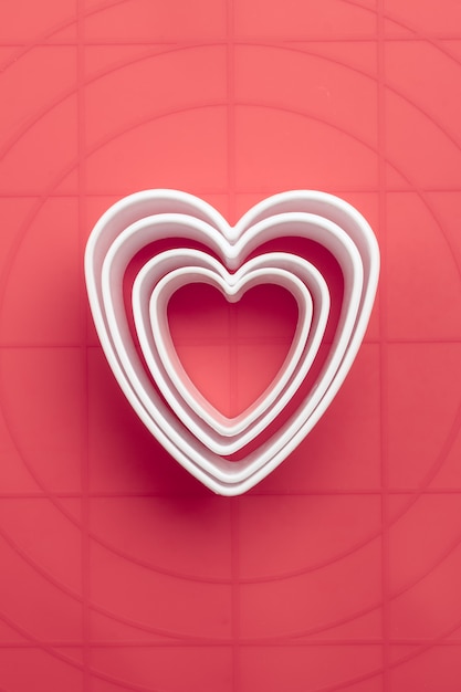 White heart symbol cookie cutters on coral background