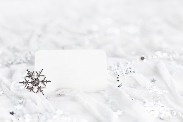 White holiday background with sparkling silver snowflakes, christmas decorations and clear piece of paper