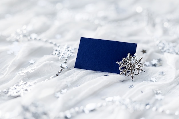 White holiday background with sparkling silver snowflakes, christmas decorations and empty piece of paper 