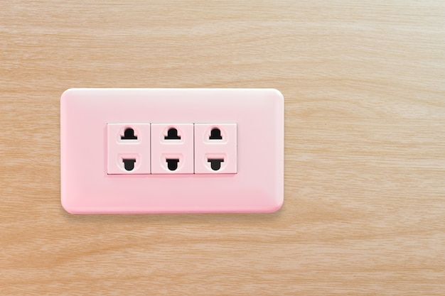 A white home electrical outlet on a wooden wall