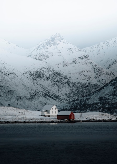 White house and a red cabin by the lake in wintertime