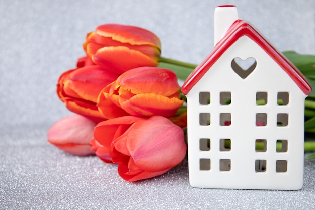 A white house with a red roof and tulips on a silver backgroundThe theme of love and celebration