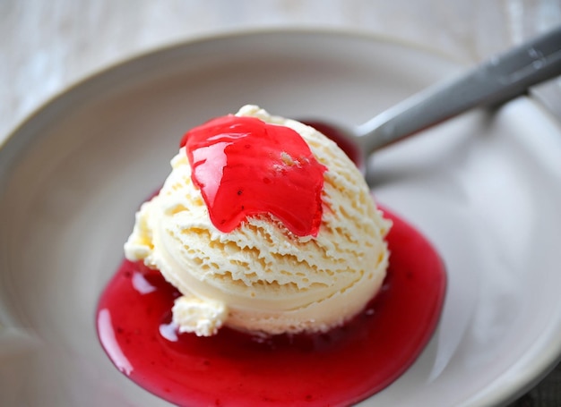 White ice cream scoop in a bowl with red syrup and a spoon ai generated