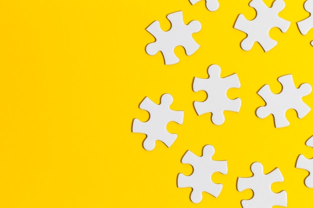 White jigsaw puzzle pieces on a yellow background Business solution concept