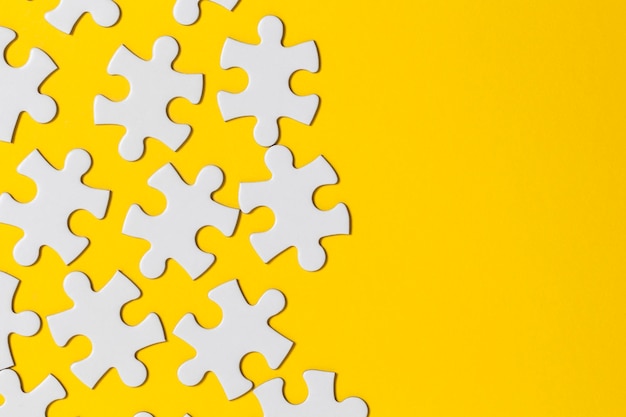 White jigsaw puzzle pieces on a yellow background Business solution concept