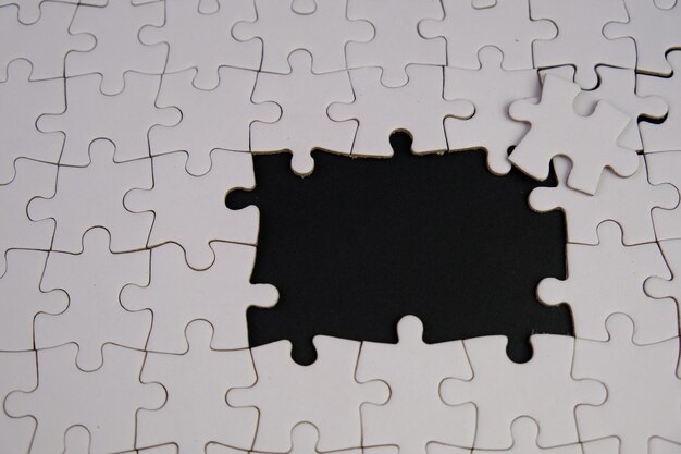 Photo white jigsaw puzzle with missing puzzle for a text template above photo of isolated black background