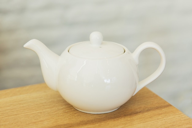 White kettle on wooden table in a restaurant. Teapot on a table