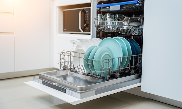 The white kitchen and opened dishwasher with clean dishes