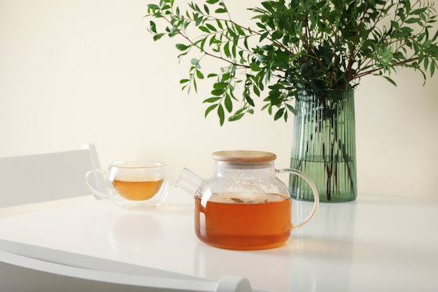 White kitchen table with tea and plant in bright room