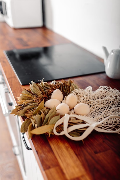 White kitchen with eggs and gift box Happy easter card with wooden eggs Mesh shopper with eggs