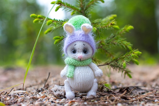 A white knitted bunny is sitting by a green Christmas tree Knitted toys for children